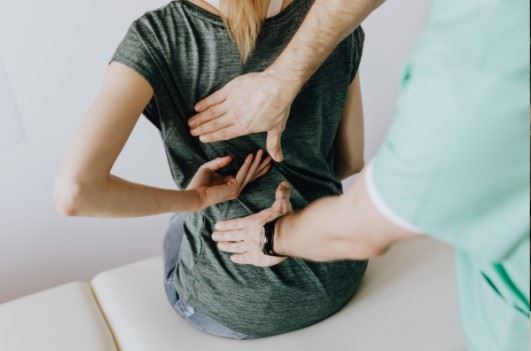 young woman having her back injury examined